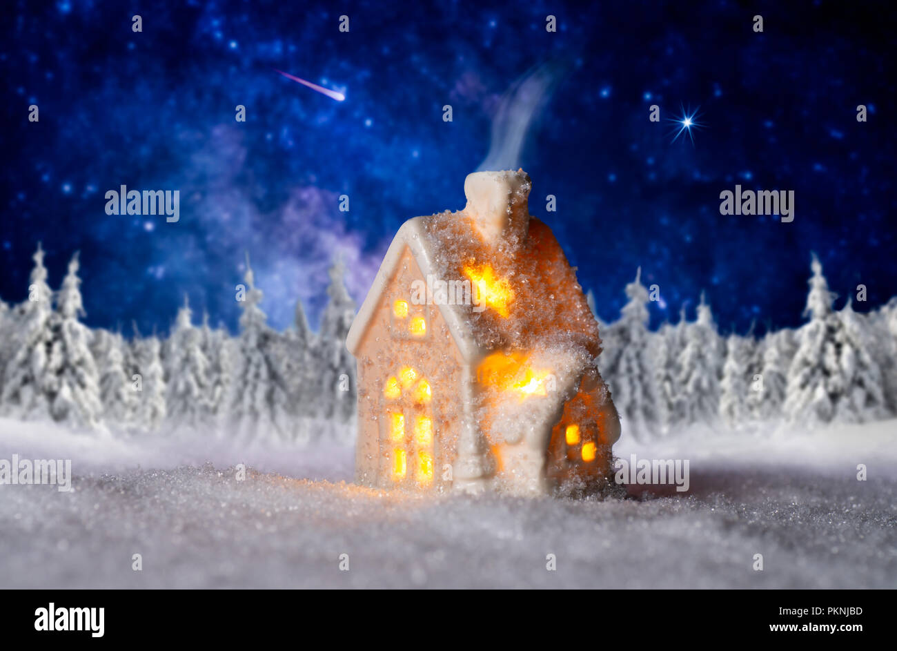 Kleines Beleuchtetes Haus mit Winterlandschaft und Sternenhimmel im Hintergrund Stockfoto