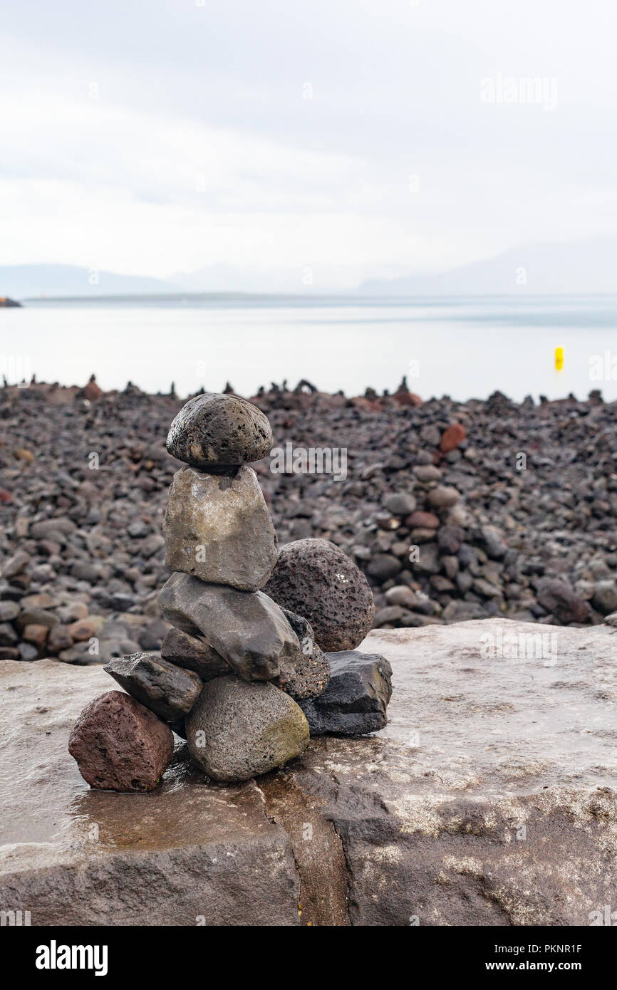 Zen - wie Cairns aus Lavagestein von Touristen gebaut auf der Uferpromenade in Reykjavik, mit Blick über die Bucht von Faxa auf die Halbinsel Snaefellsnes, Island Stockfoto