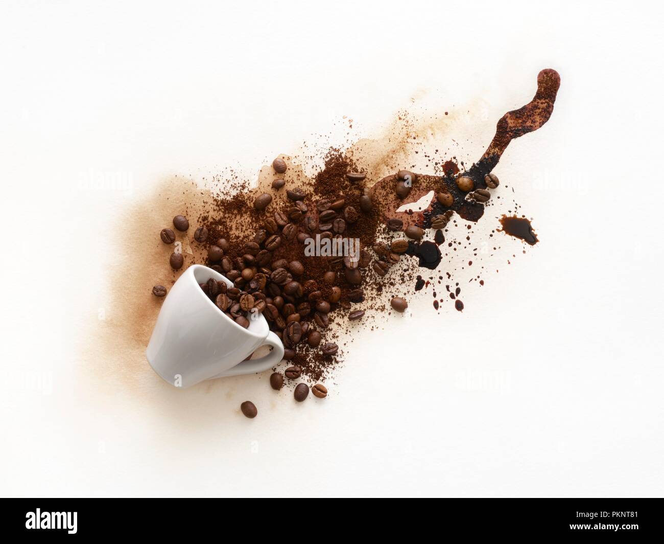 Tasse Kaffee Verschütten von Flüssigkeiten und Bohnen, die herauskommen. Stockfoto