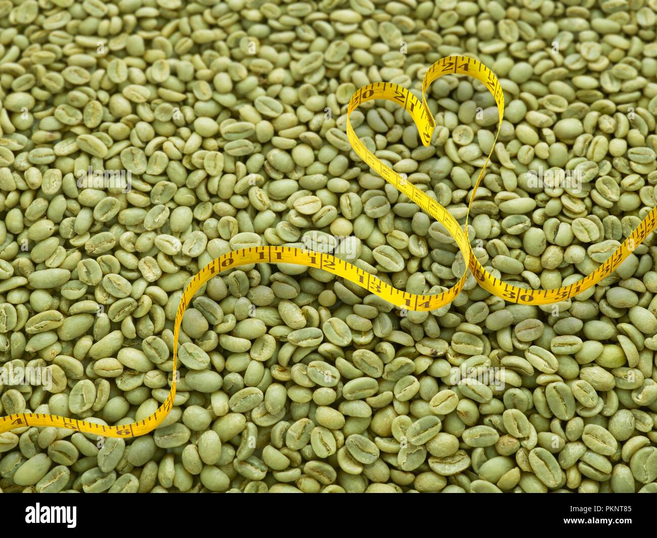 Grüne Kaffeebohnen und Herzform Maßband. Stockfoto