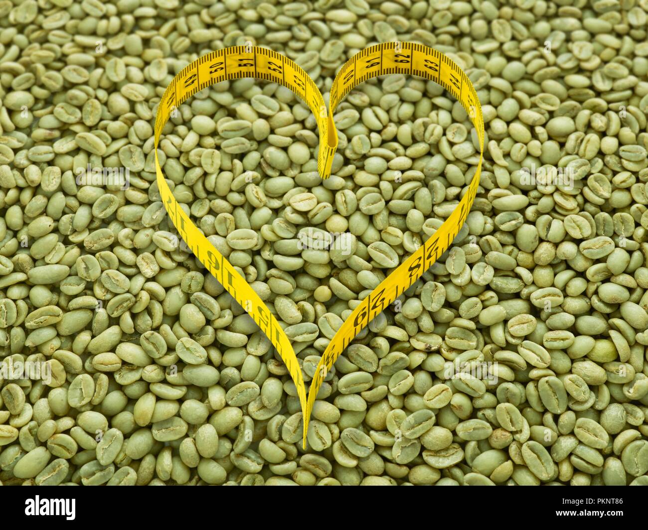Grüne Kaffeebohnen und Herzform Maßband. Stockfoto