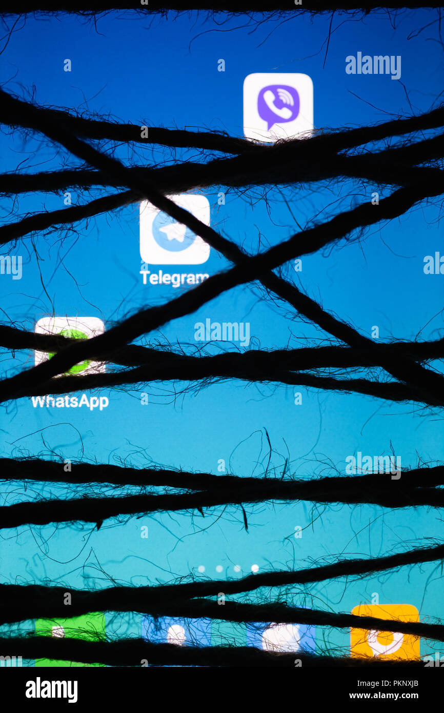 Moskau, Russland - 14. September 2018: Smartphone im Dunklen, dicht gewickelt und mit groben Jute Bondage Seil gebunden liegt mit einem leuchtenden blauen Bildschirm wi Stockfoto