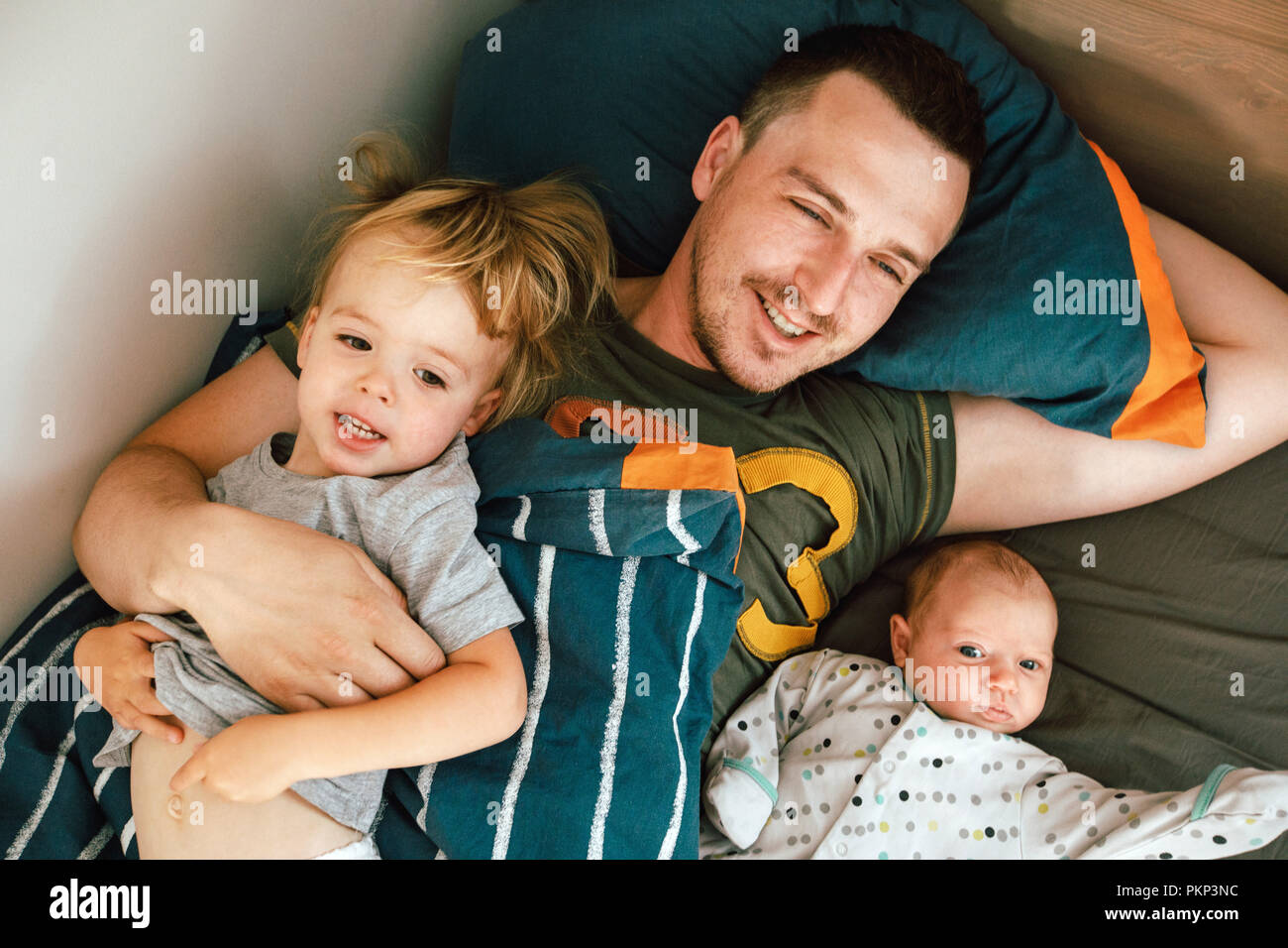 Junger Mann im Bett liegend mit Kindern Stockfoto