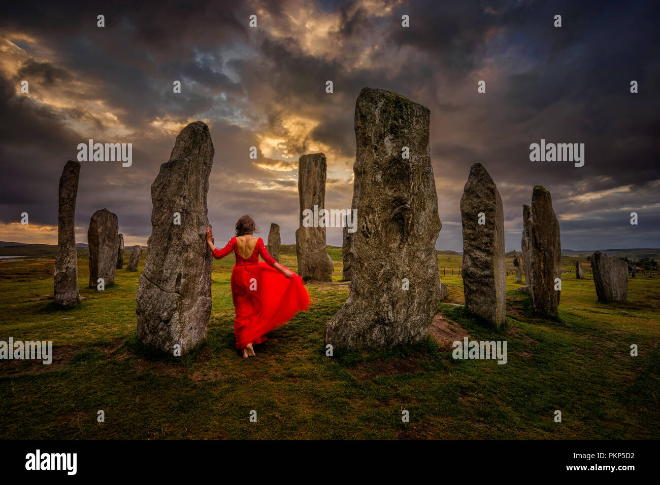 Die Frau im roten Kleid an Callanish stones im Abendlicht, Lewis, Schottland Stockfoto