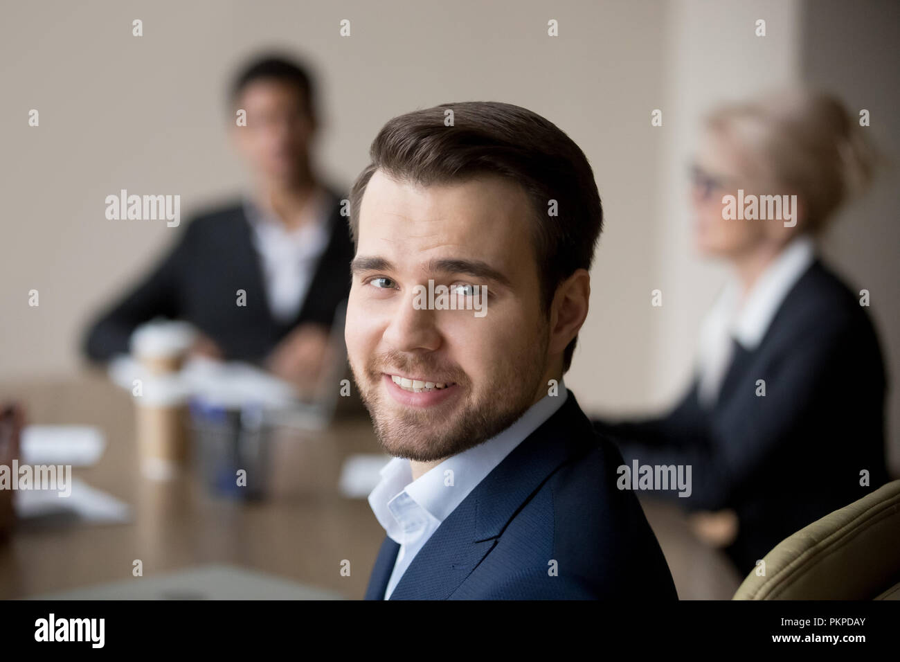 Lächelnd Geschäftsmann am Schreibtisch im Büro suchen Kamera Stockfoto