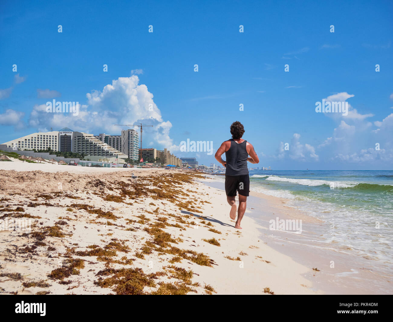 Junger Mann Jogging auf Tropical Beach Paradise Playa Delfines, Cancun, Mexiko, 7. September 2018 Stockfoto