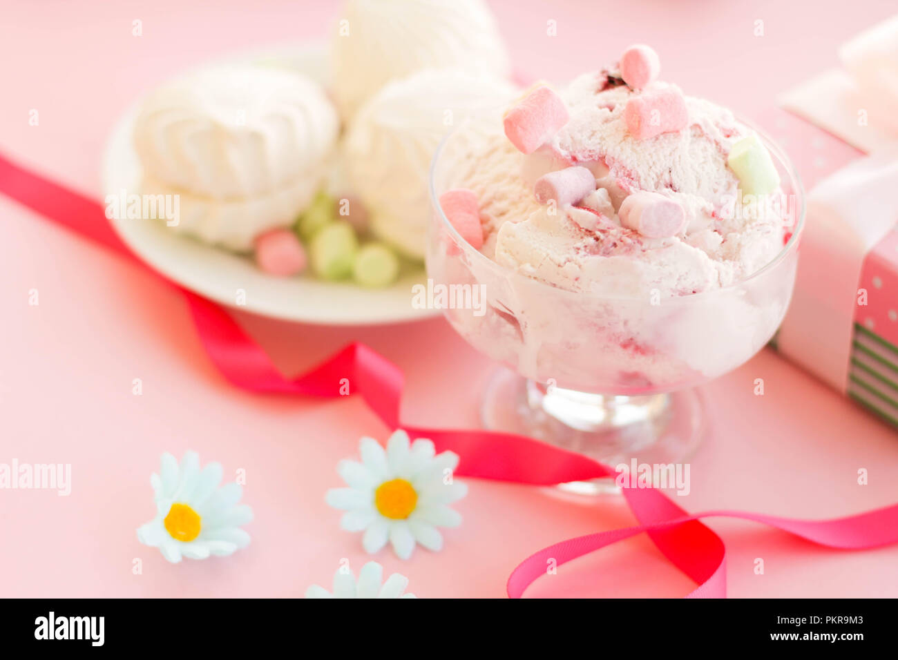 Eis in einer Schale, die neben der Marshmallows, Blumen, rosa Süßigkeiten. Stockfoto