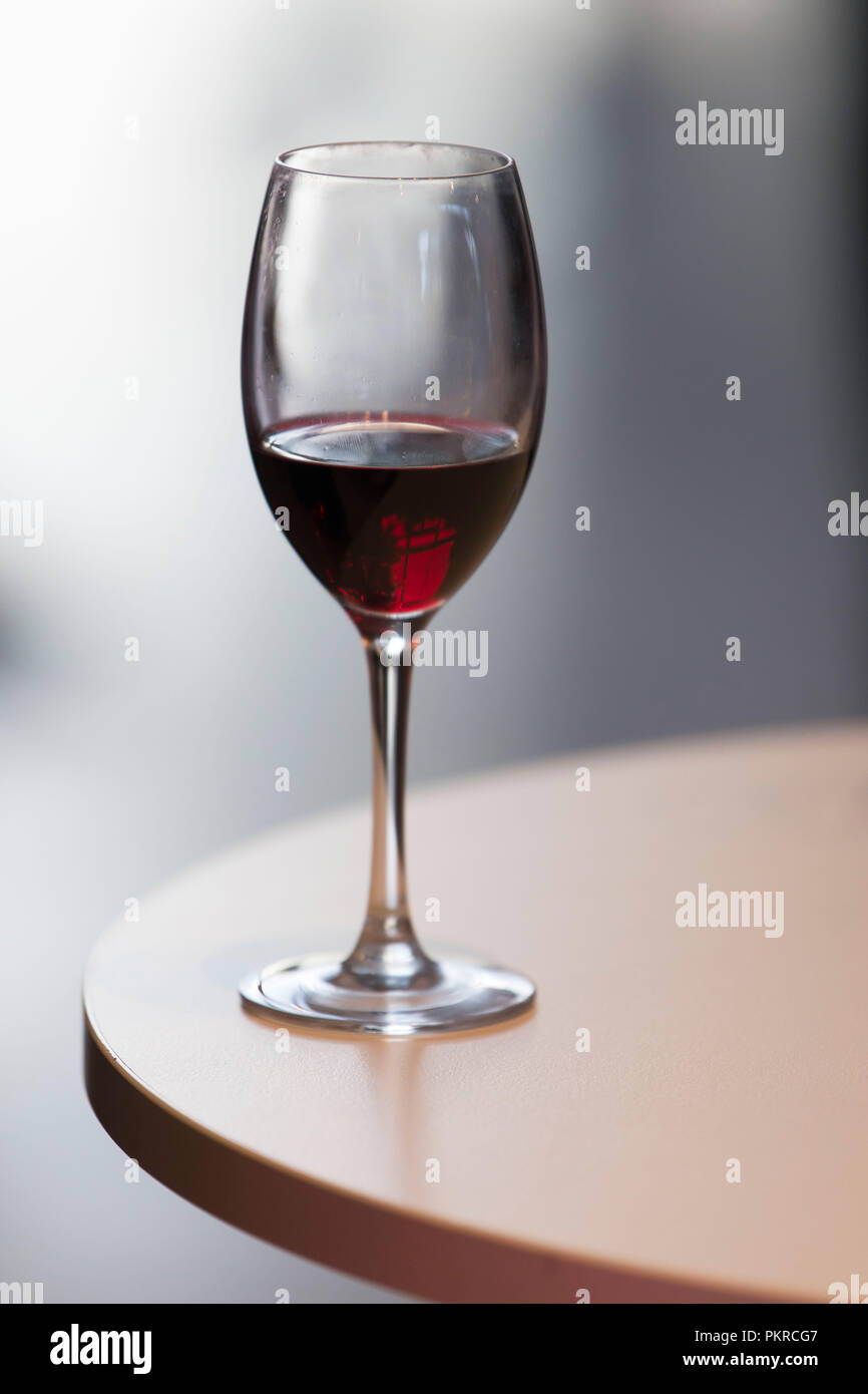 Halb leeren Glas Rotwein auf einem Holztisch mit einem Unscharf verschwommenen Hintergrund. Stockfoto