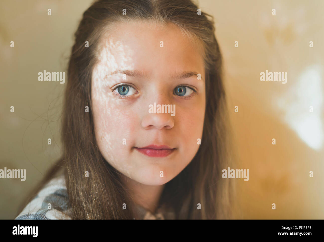Ruhiges kind Mädchen Porträt im Innenbereich mit Fenster Vorhang Schatten auf dem Gesicht Stockfoto