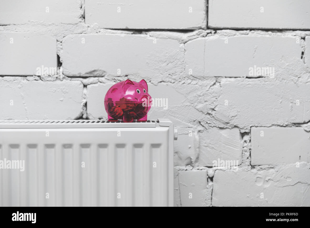Heizkosten - piggy Bank am Kühler vor der weißen Wand Stockfoto Heizkosten - piggy Bank am Kühler vor der weißen Wand Stockfoto