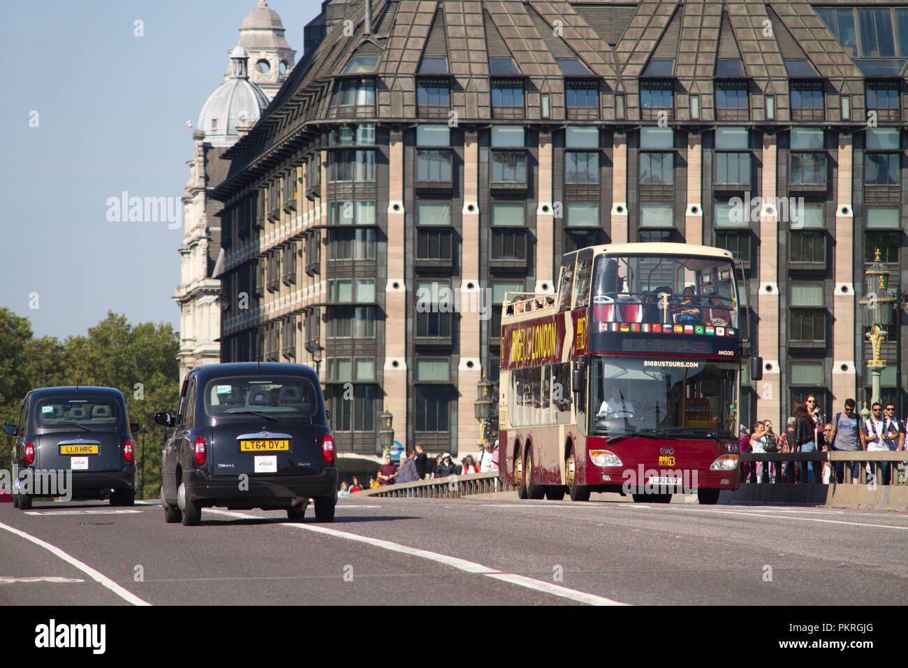 Eine Anhui Ankai teilweise offenen Bus Betrieb für Bug Bus Touren vorbei an zwei schwarzen Londoner Taxis auf die Westminster Bridge in London. Stockfoto