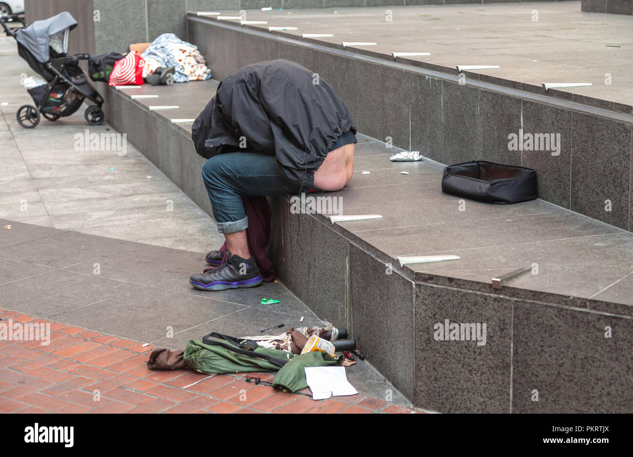 Ein obdachloser Mann schläft auf der Straße einzudämmen in San Francisco, Kalifornien, USA. Stockfoto