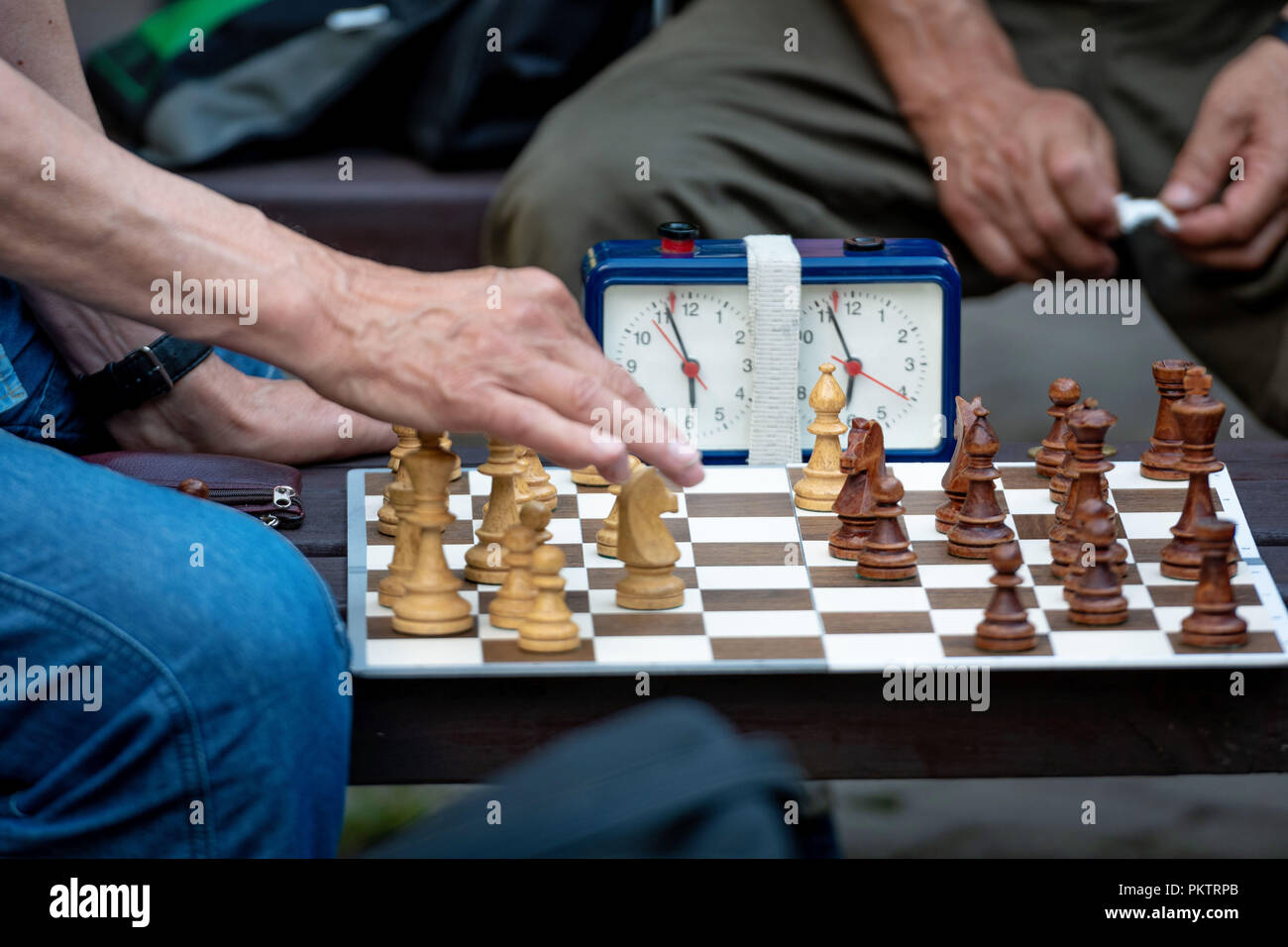 Die Leute sitzen im Park auf Bänken und Schach spielen. Stockfoto