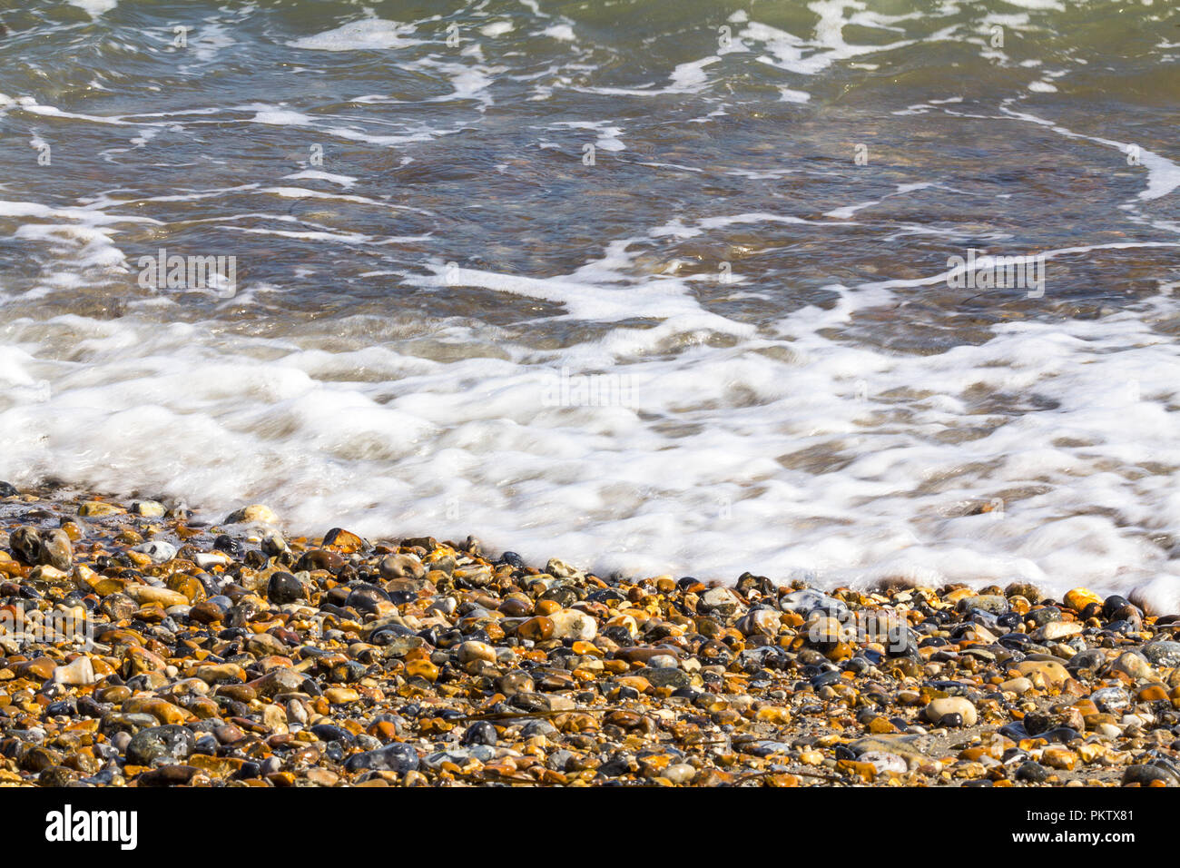 Am Strand von Pagham Harbour Tide in kommen. Kleine Wellen Steine und Muscheln im Spätsommer Surfen. Einfache calming Waters Edge Bild UK South Coast. Stockfoto