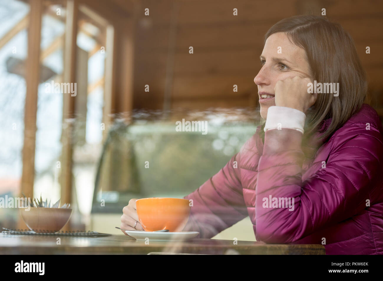 Profil anzeigen von eine junge Frau sitzt in einer Bar alleine Kaffee trinken und ihr Kopf lehnte sich auf ihre Hand. Stockfoto