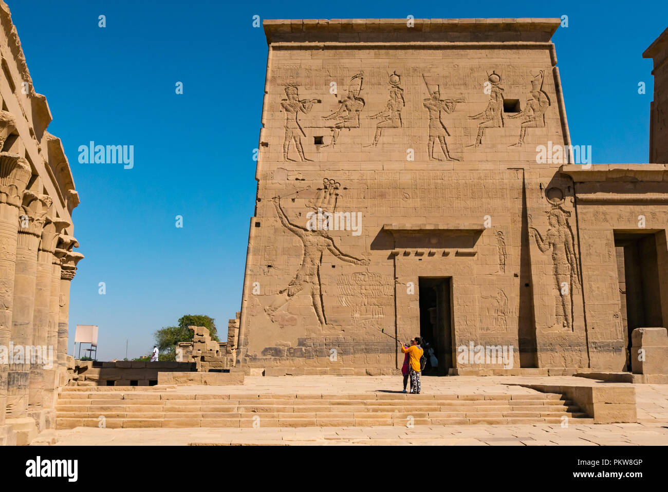 Zwei Frauen Touristen unter selfie mit selfie Stick am äußeren Pylon, Tempel von Philae, der Nil, Assuan, Ägypten, Afrika Stockfoto
