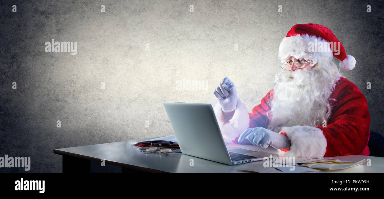 Santa Claus Schreiben mit Laptop Stockfoto