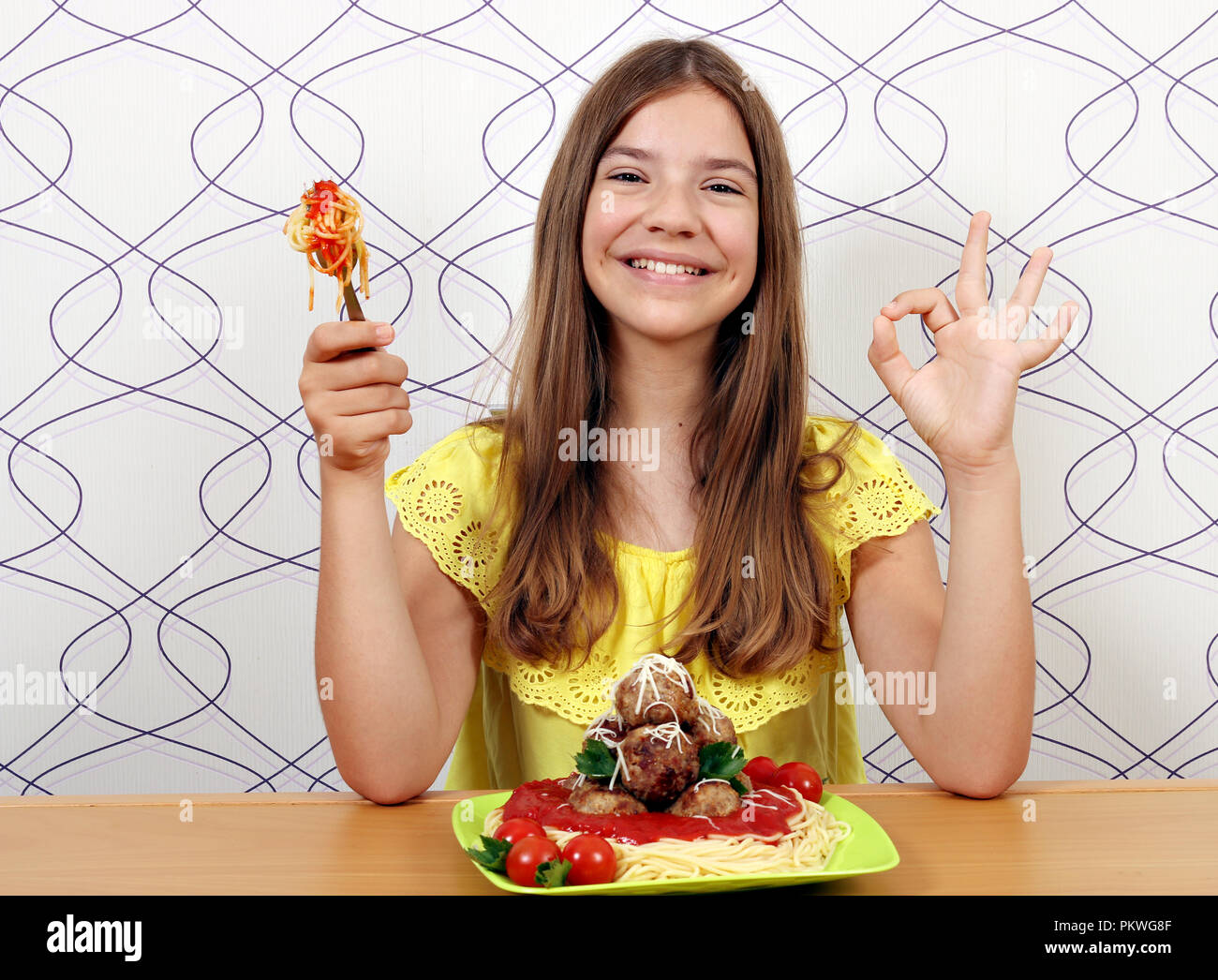 Schöne glückliche Mädchen mit Frikadellen und Spaghetti und ok Handzeichen Stockfoto