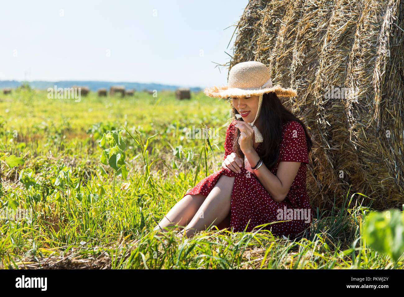 Asiatische Mädchen Entspannung im Freien in einem Weizenfeld das Tragen der roten Kleid Stockfoto