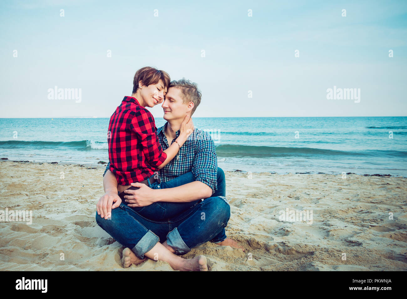 Portrait von Glückliches Paar am Strand. Junger Mann und Frau sitzt auf der sandigen Küste und umarmen. Konzept der Liebenden glücklichen Momente auf Urlaub, Ferien. T Stockfoto