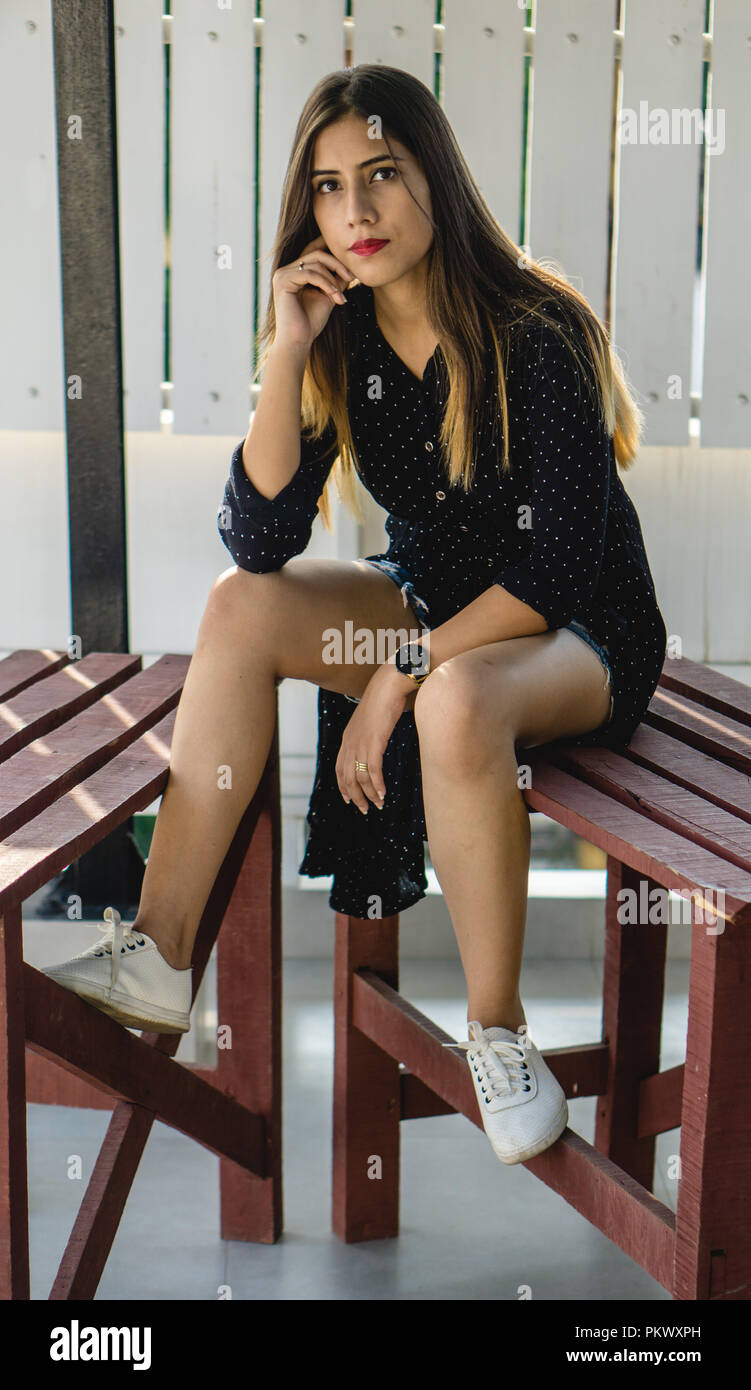Girl posiert für die Kamera, während er auf dem Holztisch in einen Balkon. Stockfoto