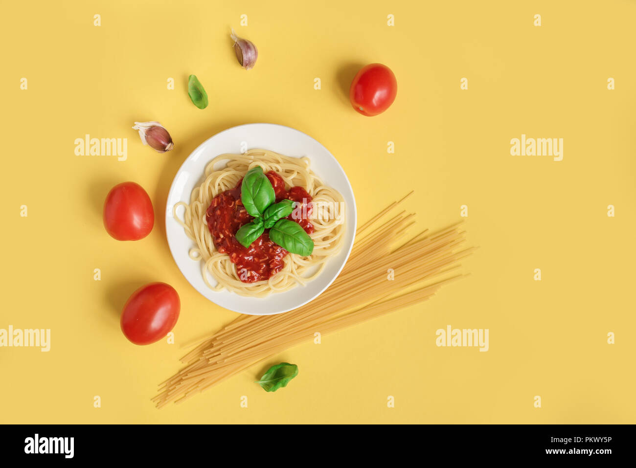 Spaghetti Spaghetti Bolognese und Zutaten auf gelbem Hintergrund, Ansicht von oben. Teller Pasta mit Tomatensauce und Basilikum auf kreative Gelb backgroun Stockfoto