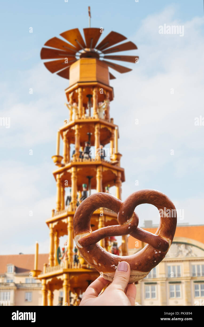 Das Mädchen ist eine traditionelle deutsche Brezel in der Hand. Dekorationen ein Weihnachtsmarkt im Hintergrund. Stockfoto