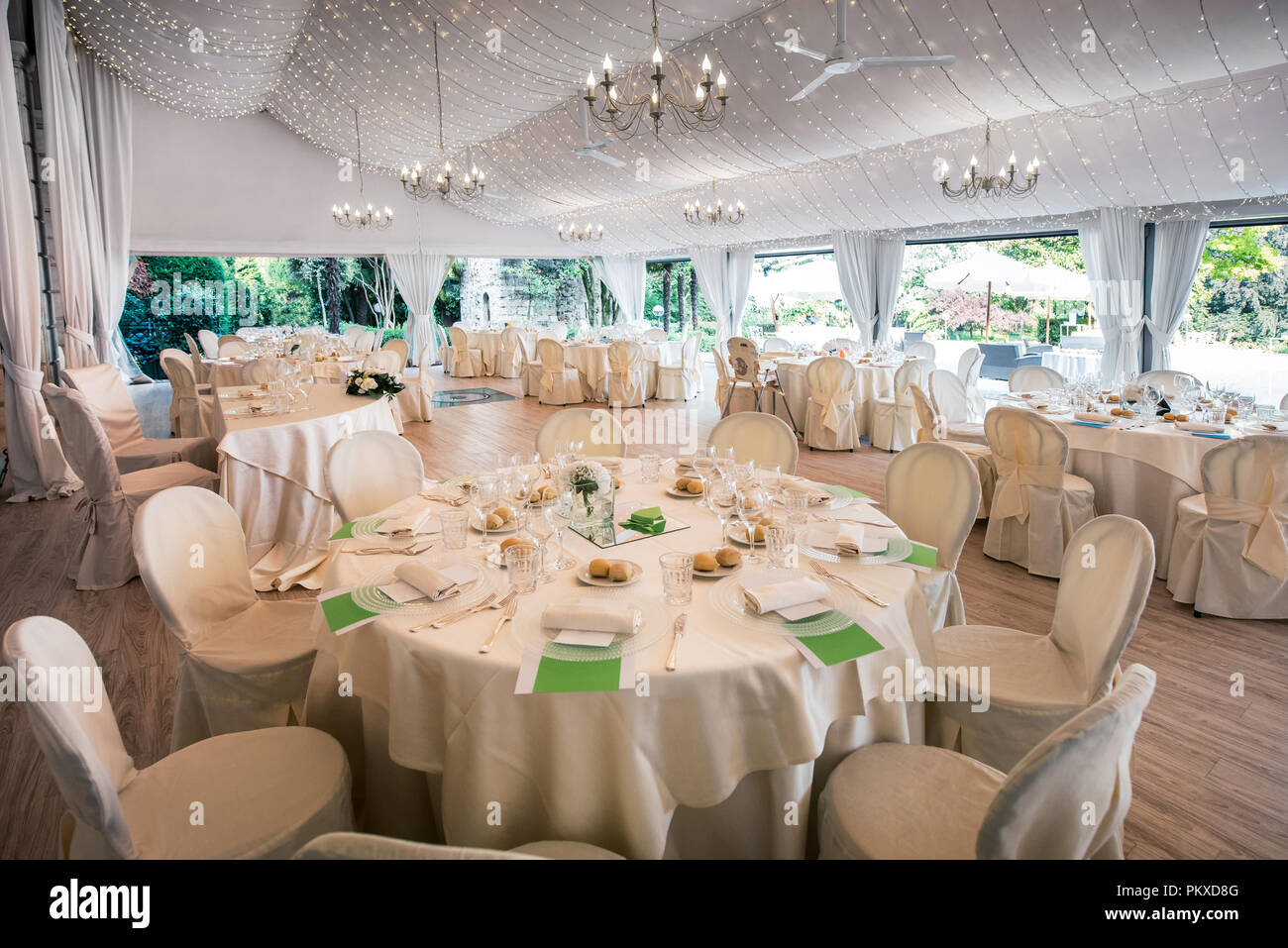 Hochzeit Veranstaltungsort in einer großen Marquis mit eleganten formale weiße Tabelle Einstellungen und Blick auf einen Garten Stockfoto