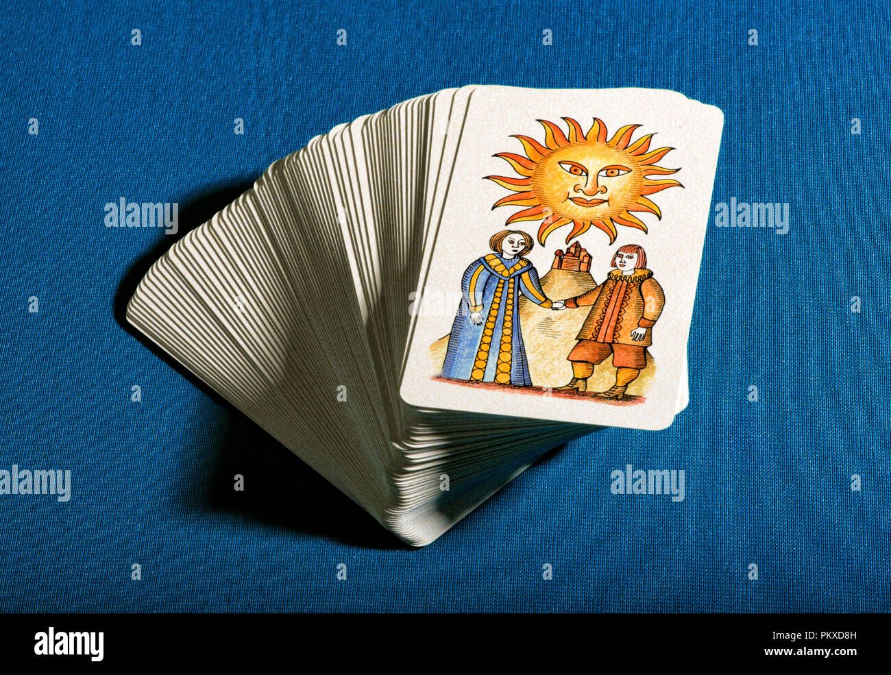 Deck gestapelt tarot Karten mit der bildlichen Darstellung der Karte Sun auf konzeptionelle von Glück und Optimismus über einen blauen Hintergrund Stockfoto