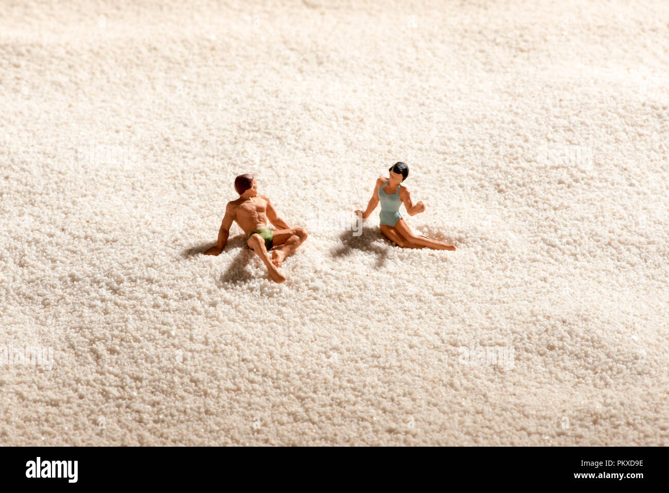 Paar miniatur Menschen entspannend an einem Sandstrand in einem konzeptionellen Bild von Sommer Ferien, Entspannung und dating Stockfoto