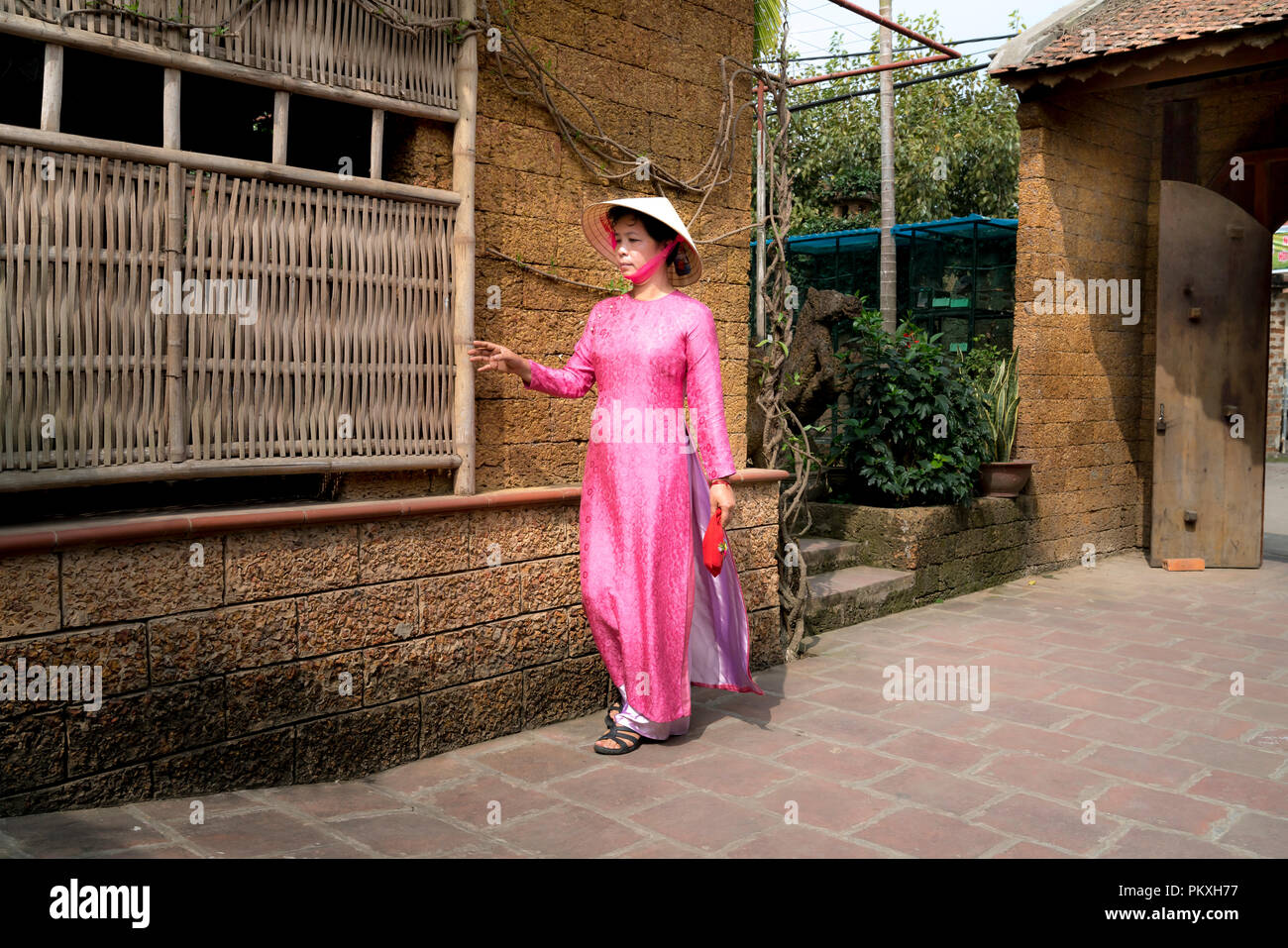 Eine charmante Frau, die in einem traditionellen Ao Dai im alten Dorf Duong Lam. Ha Noi, Vietnam Stockfoto