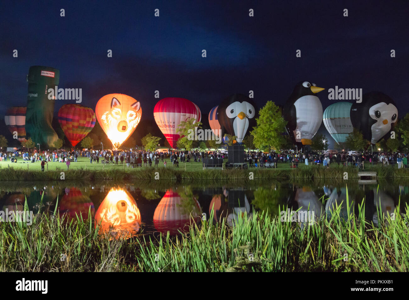 Longleat, Wiltshire, UK. 15 Sep, 2018. Nach einem erfolgreichen Tag fliegen mit dem schönen Wetter, tausende Leute zu sehen, die Heißluftballons in den nächtlichen Himmel der Himmel Longleat Safari Nacht Glühen beleuchtet. Der Ballon Festival ist das Größte in Großbritannien. Reihe von Heißluftballons, die im Dunkeln leuchten von Musik begleitet, und im Wasser des Sees spiegelt. Credit: Carolyn Jenkins/Alamy leben Nachrichten Stockfoto