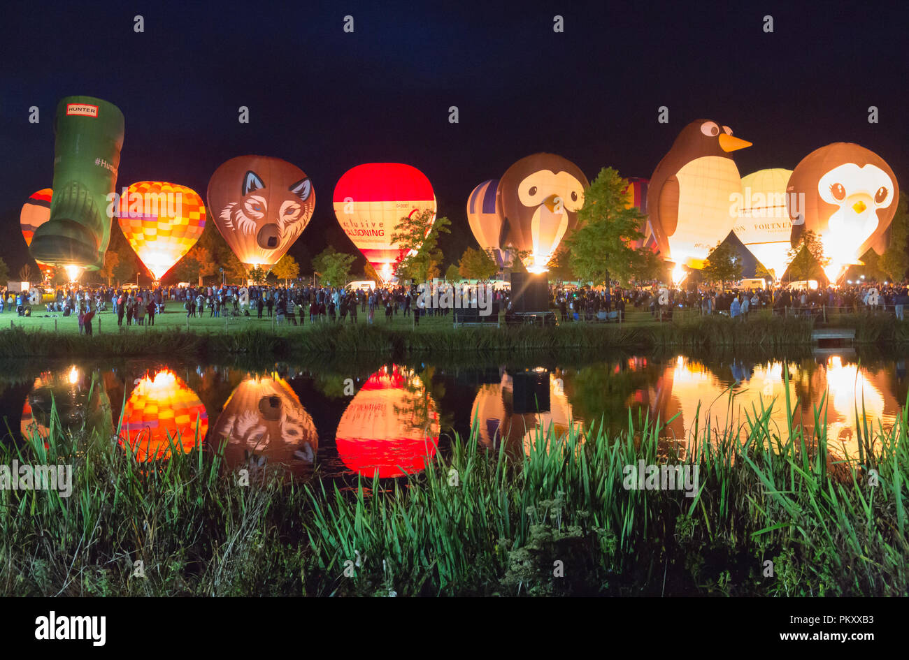 Longleat, Wiltshire, UK. 15 Sep, 2018. Nach einem erfolgreichen Tag fliegen mit dem schönen Wetter, tausende Leute zu sehen, die Heißluftballons in den nächtlichen Himmel der Himmel Longleat Safari Nacht Glühen beleuchtet. Der Ballon Festival ist das Größte in Großbritannien. Reihe von Heißluftballons, die im Dunkeln leuchten von Musik begleitet, und im Wasser des Sees spiegelt. Credit: Carolyn Jenkins/Alamy leben Nachrichten Stockfoto
