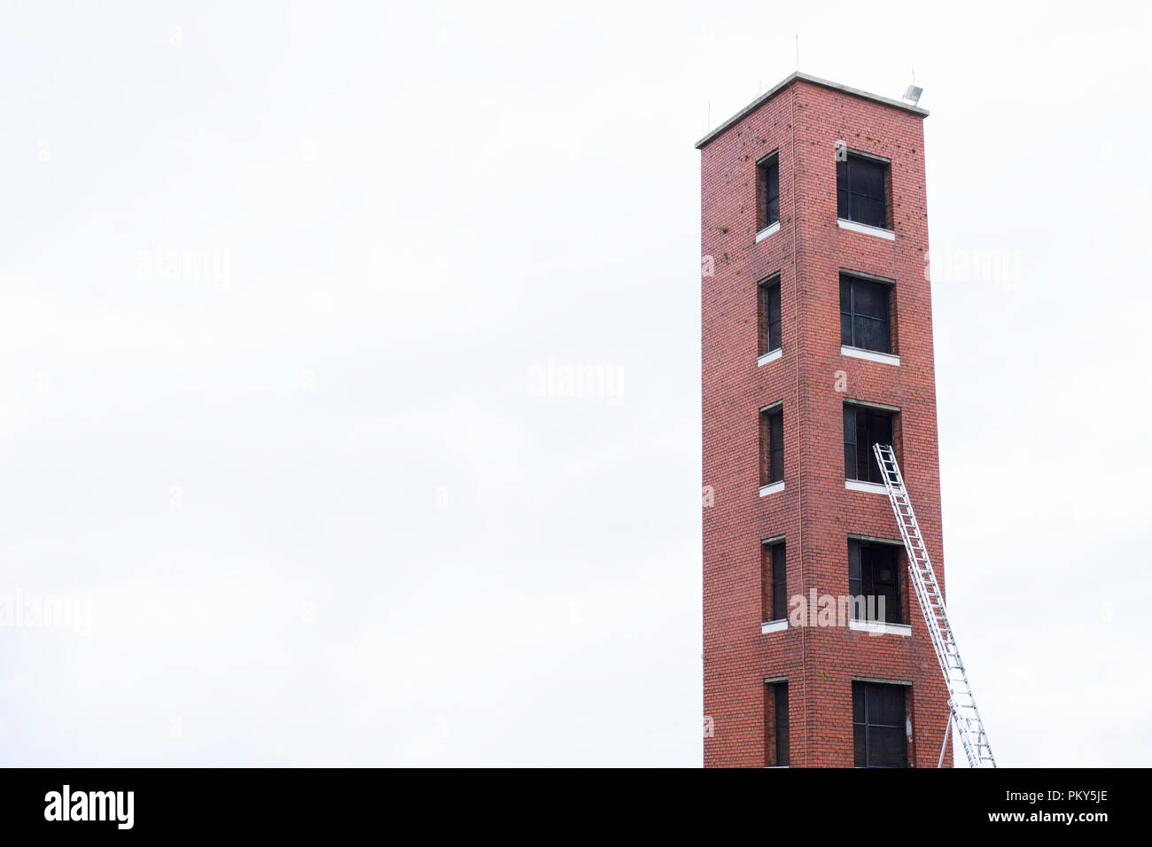 Tower für Feuerwehr Notfalltraining Praxis und Leiter gegen rote Backstein und leere Himmel Stockfoto