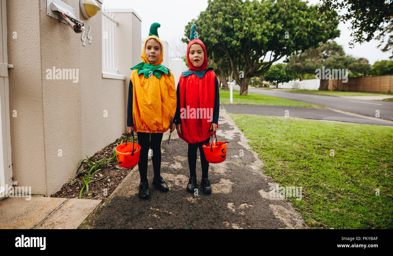 Junge Mädchen in Halloween Kostüm vor einem Haus mit halloween Schaufeln für Trick bereit oder Behandlung. Kinder in Kürbis Kostüme Trick-or-tr Stockfoto