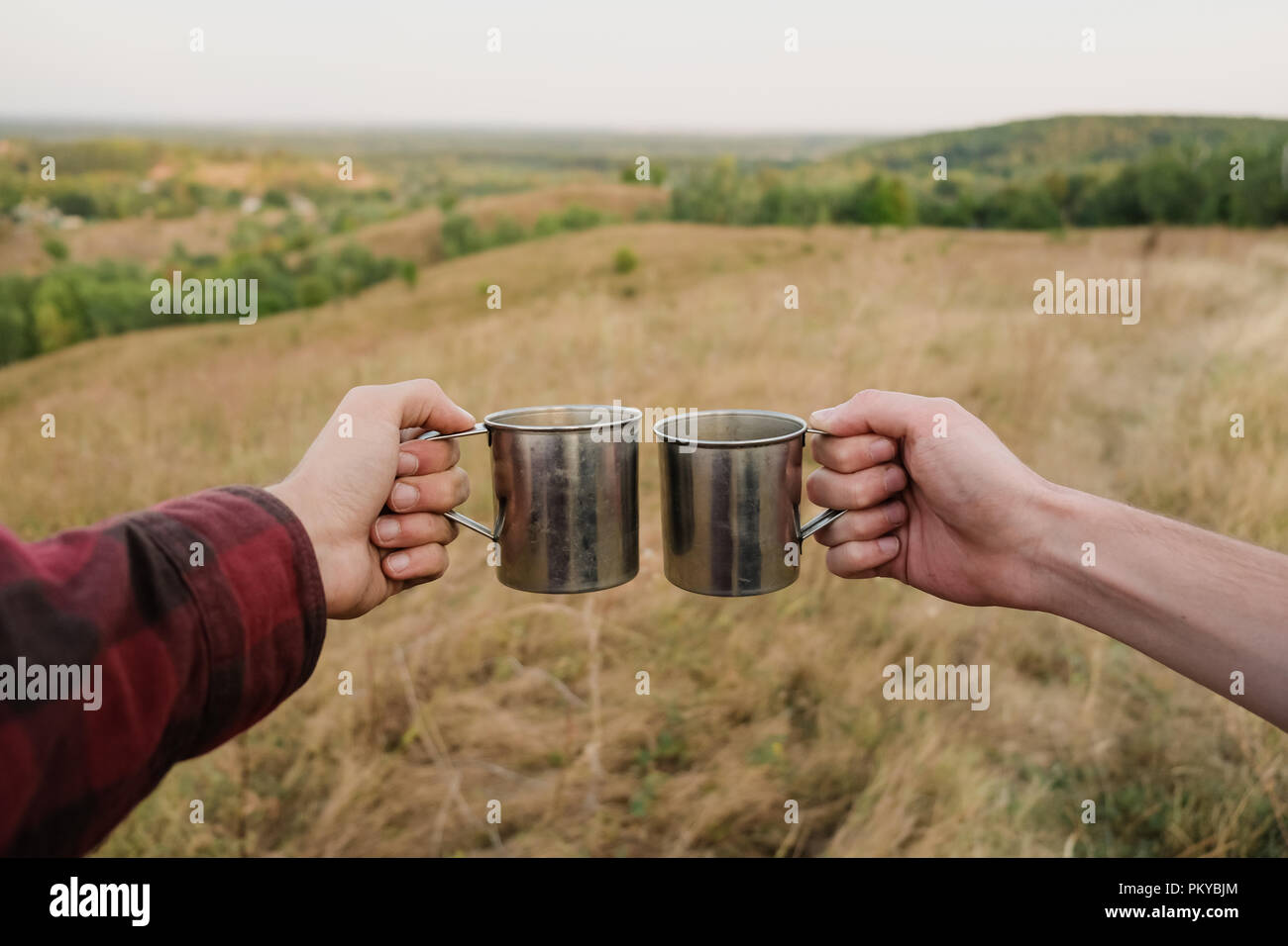 Zwei Hände halten Metall touristische Kappen in schöner Natur. Stockfoto