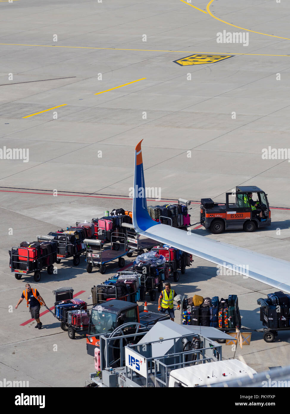 Ein Passagierflugzeug wird am Zürcher Flughafen Kloten geladen. Beschäftigte Arbeitnehmer, Gepäckwagen und Trolleys neben einem Flugzeug. Stockfoto