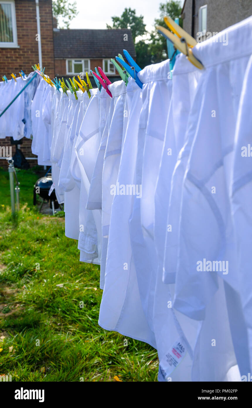 Weiße Hemden heraus hängen auf einer Wäscheleine in einem Wohngebiet zurück Garten zu trocknen. Stockfoto
