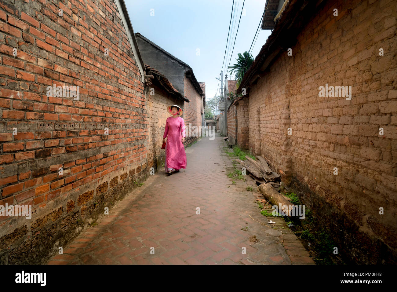 Eine charmante Frau, die in einem traditionellen Ao Dai im alten Dorf Duong Lam. Ha Noi, Vietnam Stockfoto