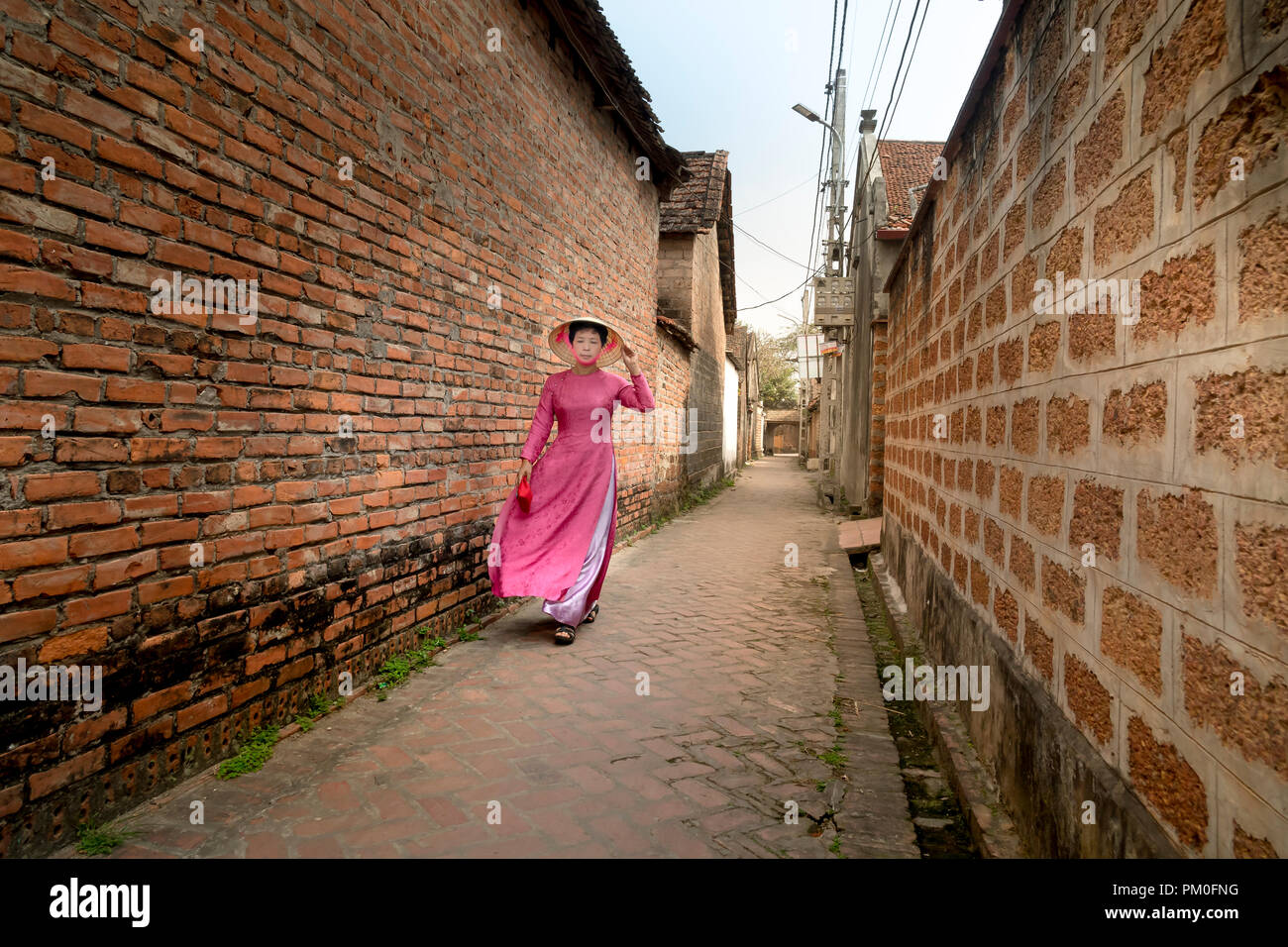 Eine charmante Frau, die in einem traditionellen Ao Dai im alten Dorf Duong Lam. Ha Noi, Vietnam Stockfoto