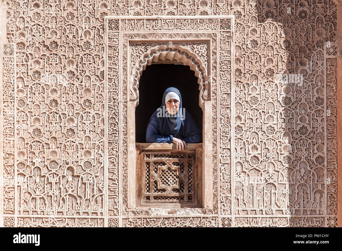 26-02-15, Marrakesch, Marokko. Eine Frau in der traditionellen Kleid sieht durch ein Fenster der Medersa Ben Youssef, oder der Sohn von Joseph an der Schule. Foto © Sim Stockfoto