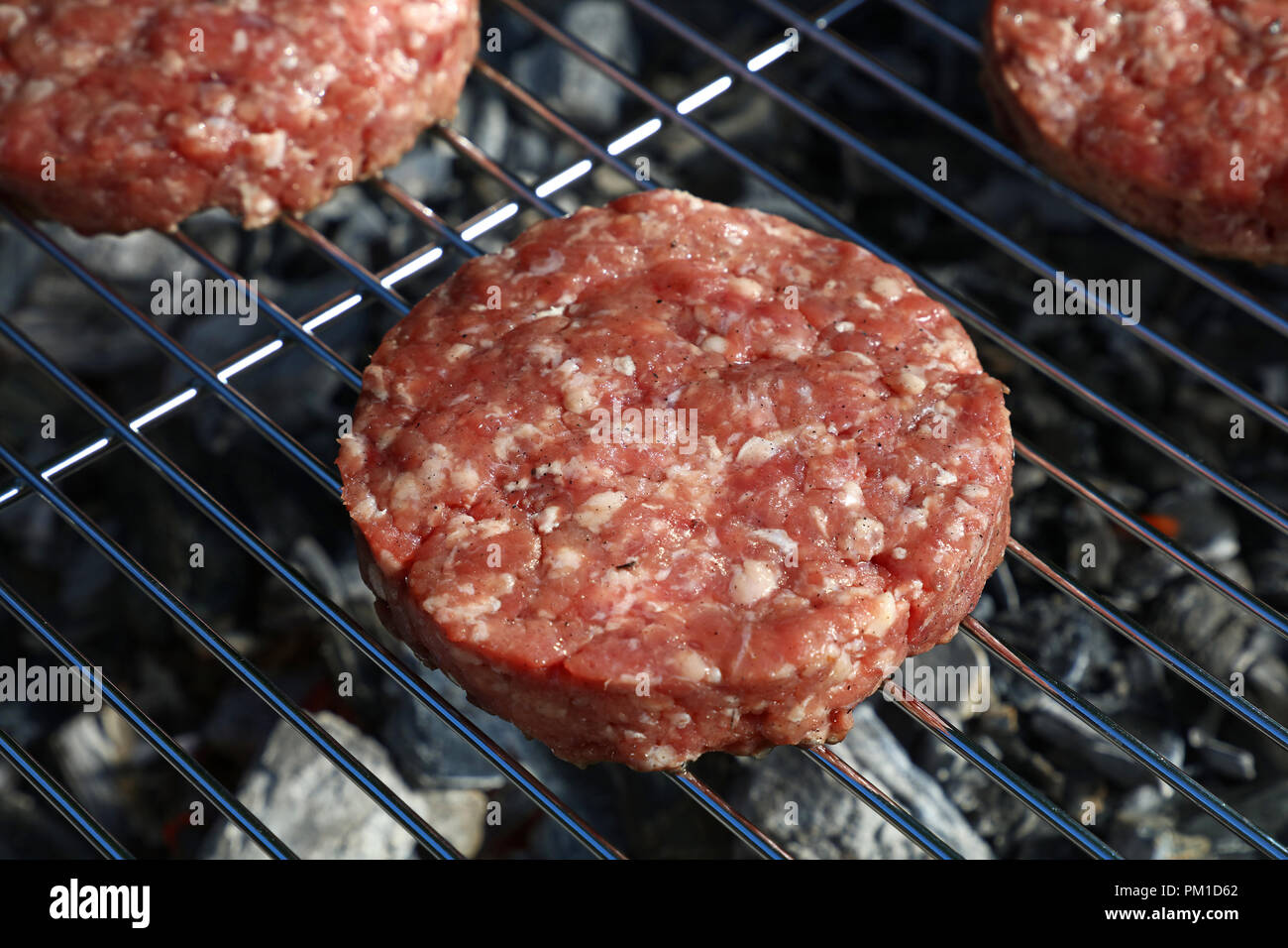 Close up rohes Rind- oder Schweinefleisch Fleisch Grill Burger für Hamburger auf BBQ Grill gekocht, gegrillt, hohe Betrachtungswinkel Stockfoto