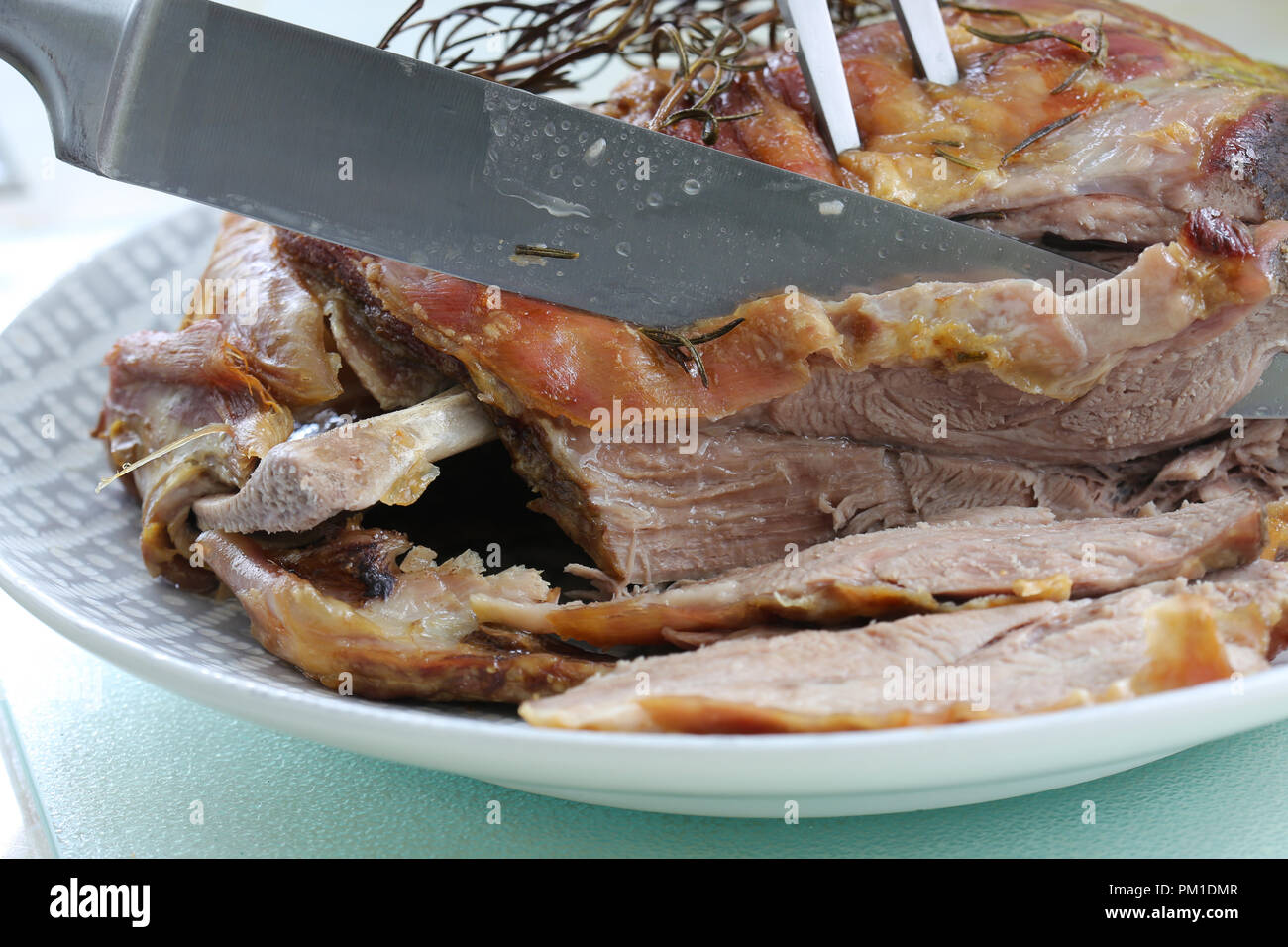 Gebratene Lammschulter mit Rosmarin Kraut garnieren mit einem Messer geschnitzt, Stockfoto