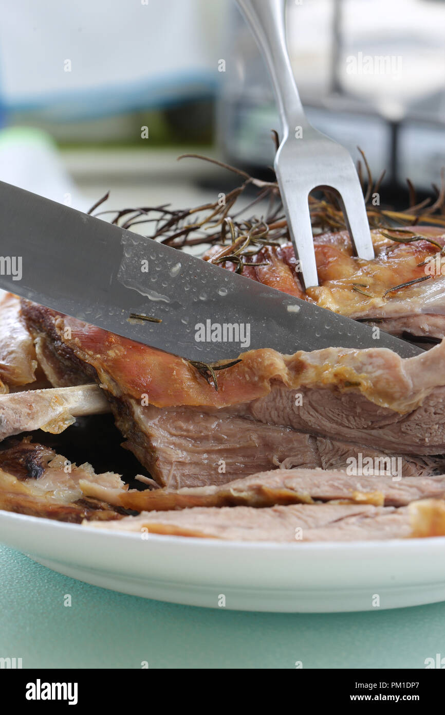 Gebratene Lammschulter mit Rosmarin Kraut garnieren mit einem Messer geschnitzt, Stockfoto