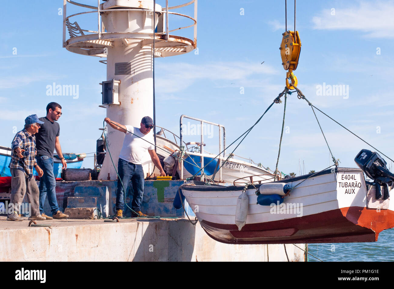 Männer heben Fischerboot in Wasser mit Bootskran setzen Stockfoto