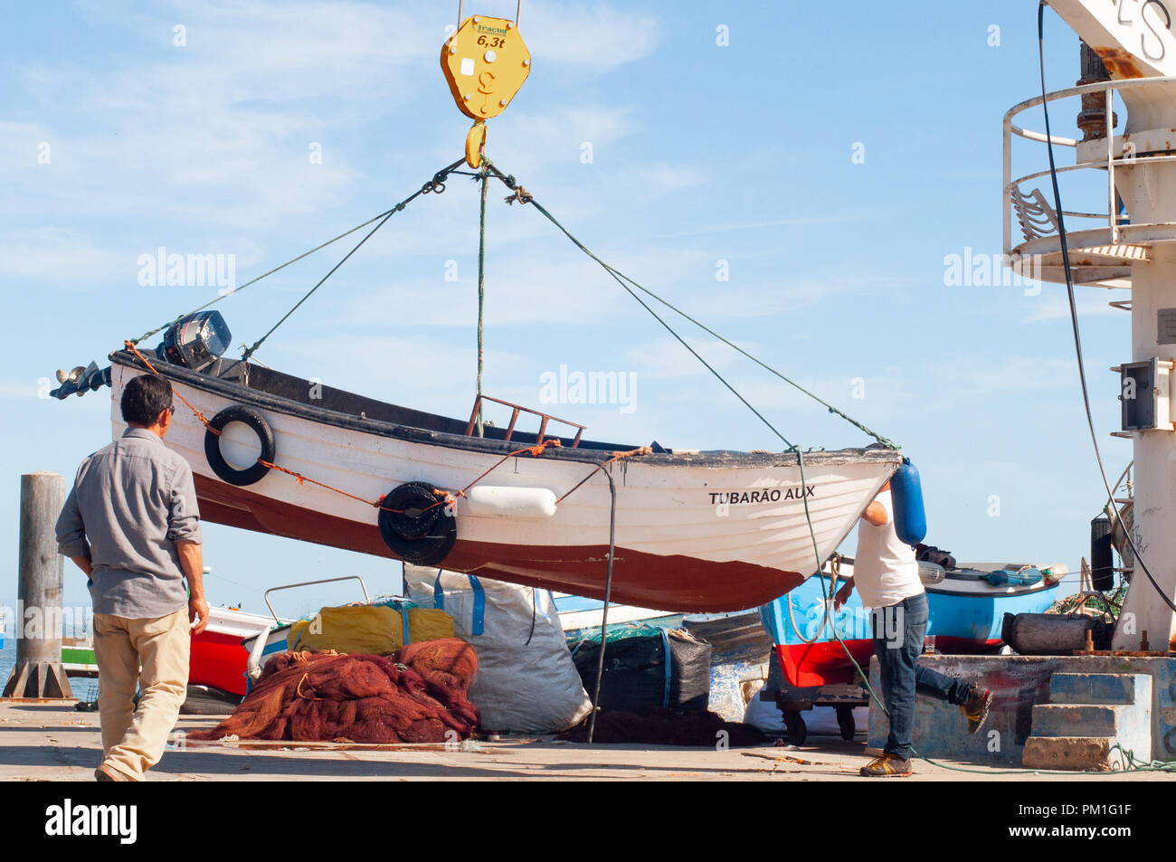 Männer heben Fischerboot in Wasser mit Bootskran setzen Stockfoto