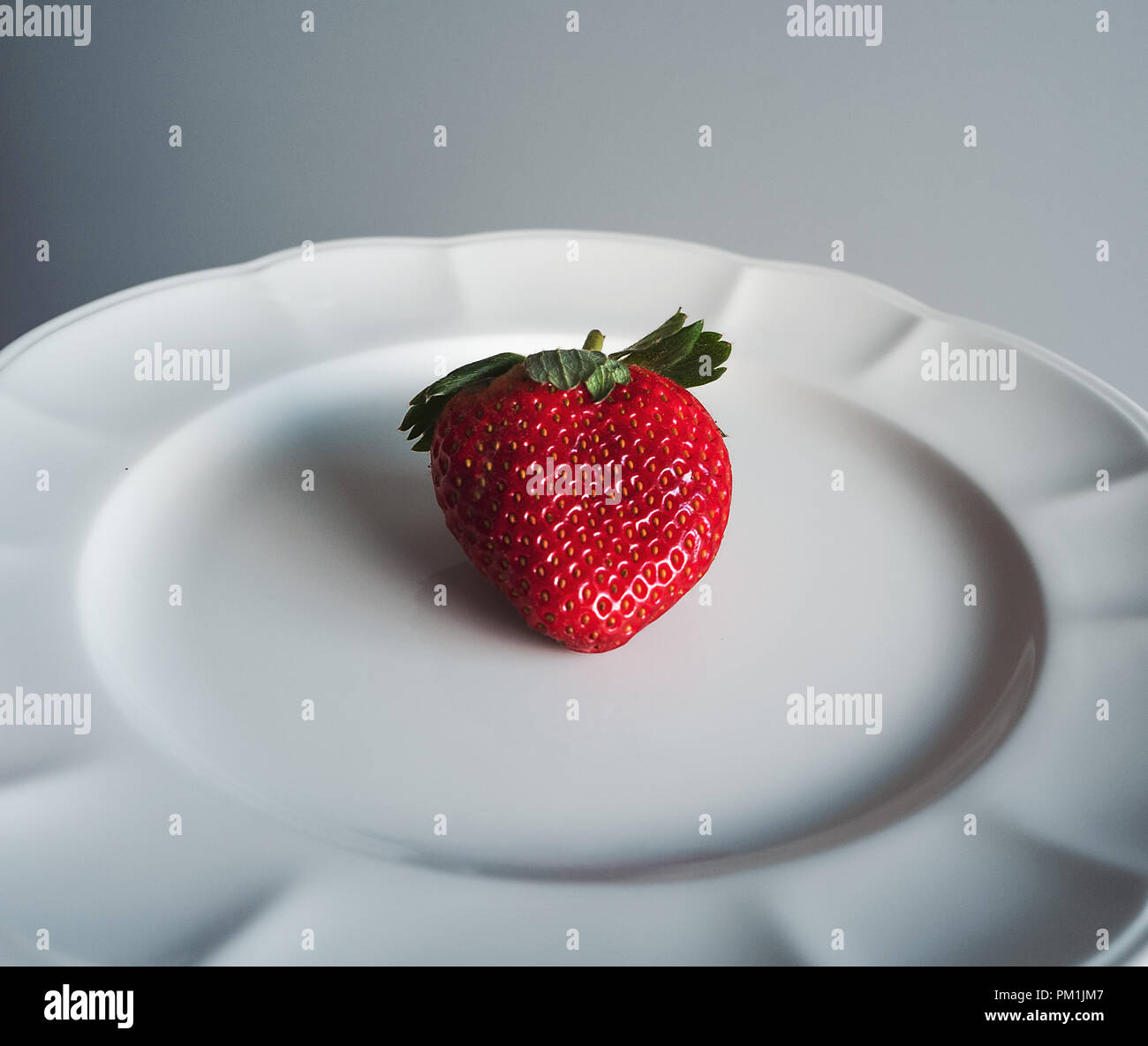 Frische rote Erdbeere auf weiße Platte Nahaufnahme gewinkelt Stockfoto
