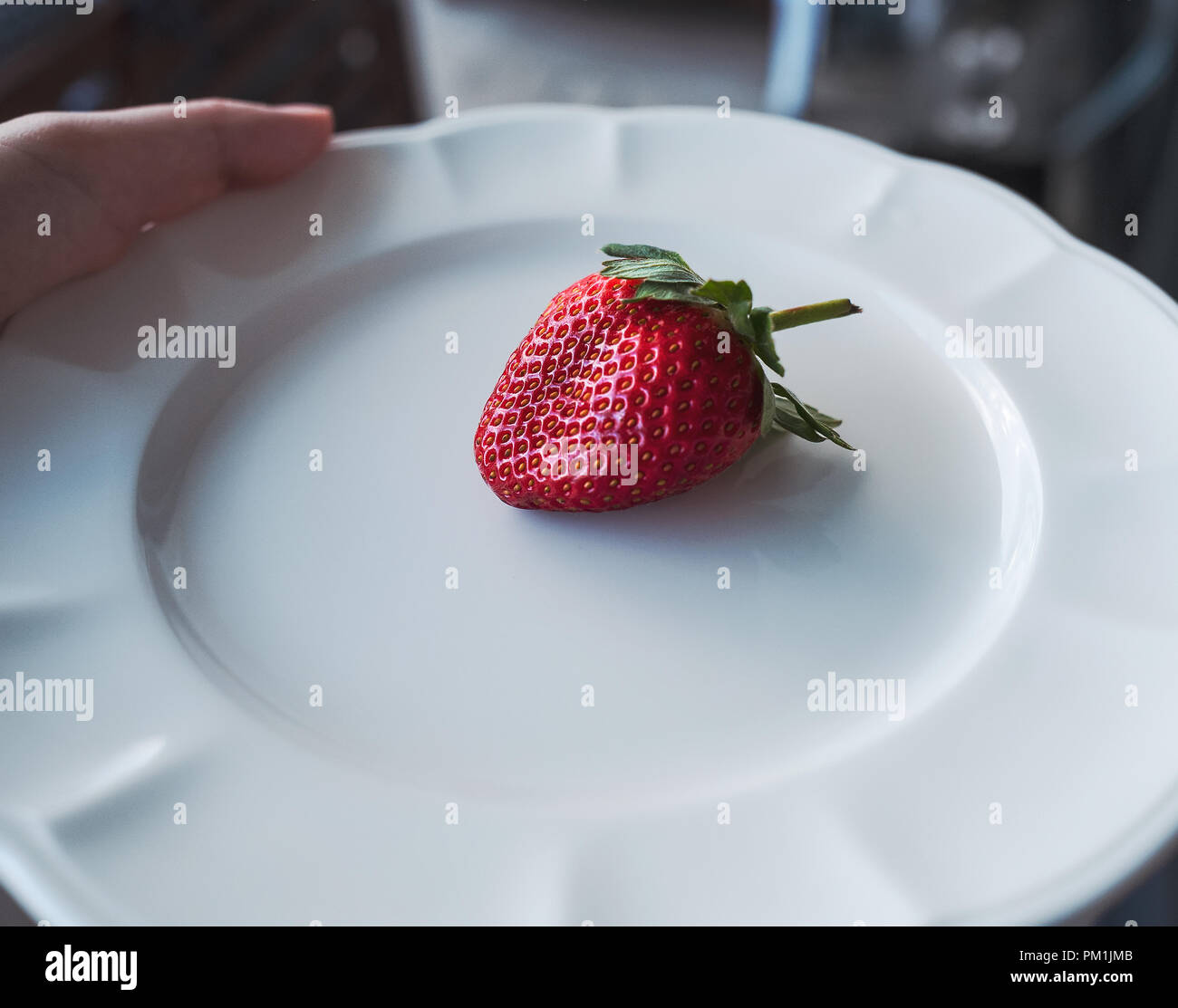 Frische rote Erdbeere auf weiße Platte mit Hand abgewinkelt Stockfoto
