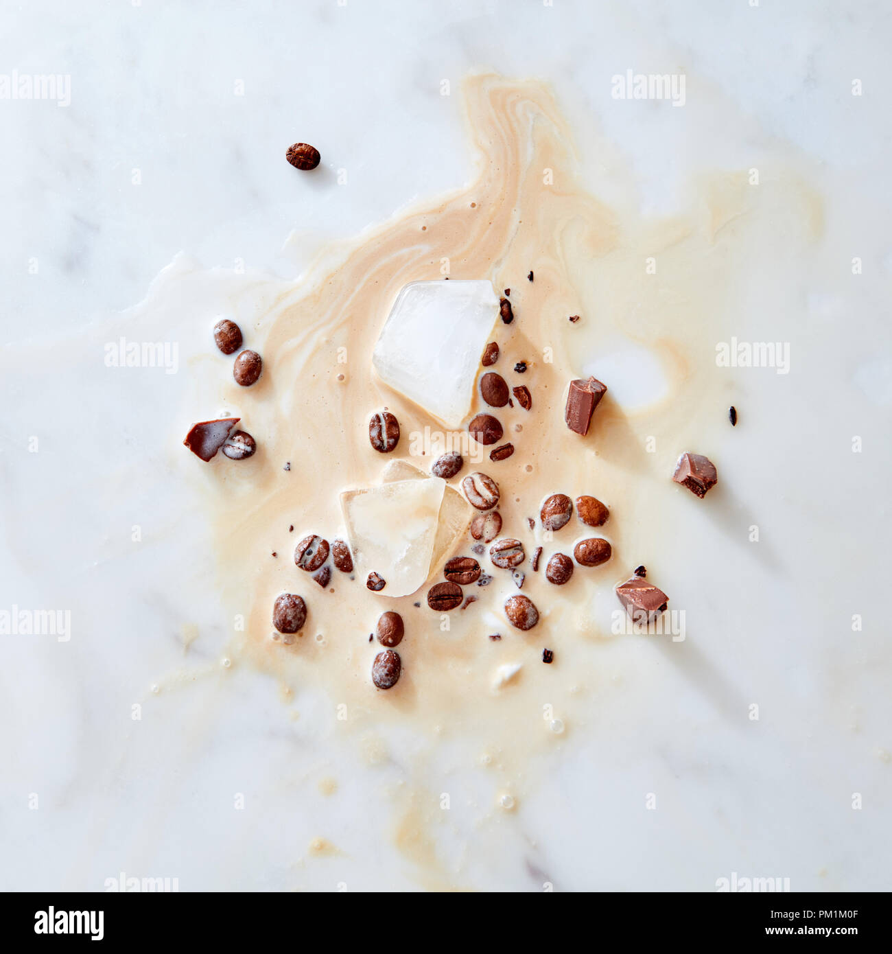 Ein Muster von Spritzern von Kaffee mit Milch Stücke Schokolade, Eis und Kaffee Körner auf grauem Marmor Hintergrund mit Platz für Text. Flach Stockfoto