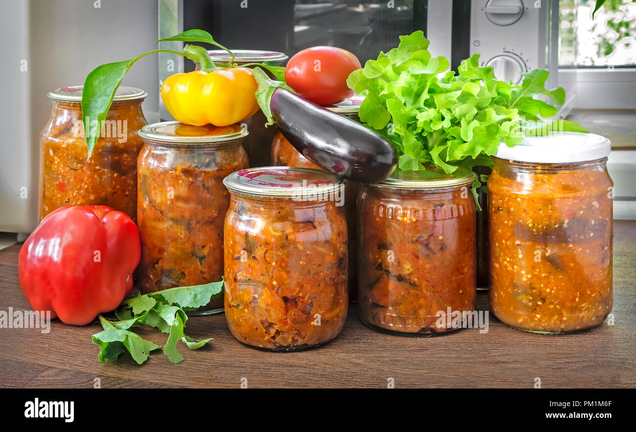 Verschiedene Gemüse in Gläsern mit abgedichteten Metallgehäuse mit Deckel: Auberginen, Paprika, Tomaten, Zwiebeln bewahrt. Frisches Gemüse und Salat sind in der Nähe von Stockfoto